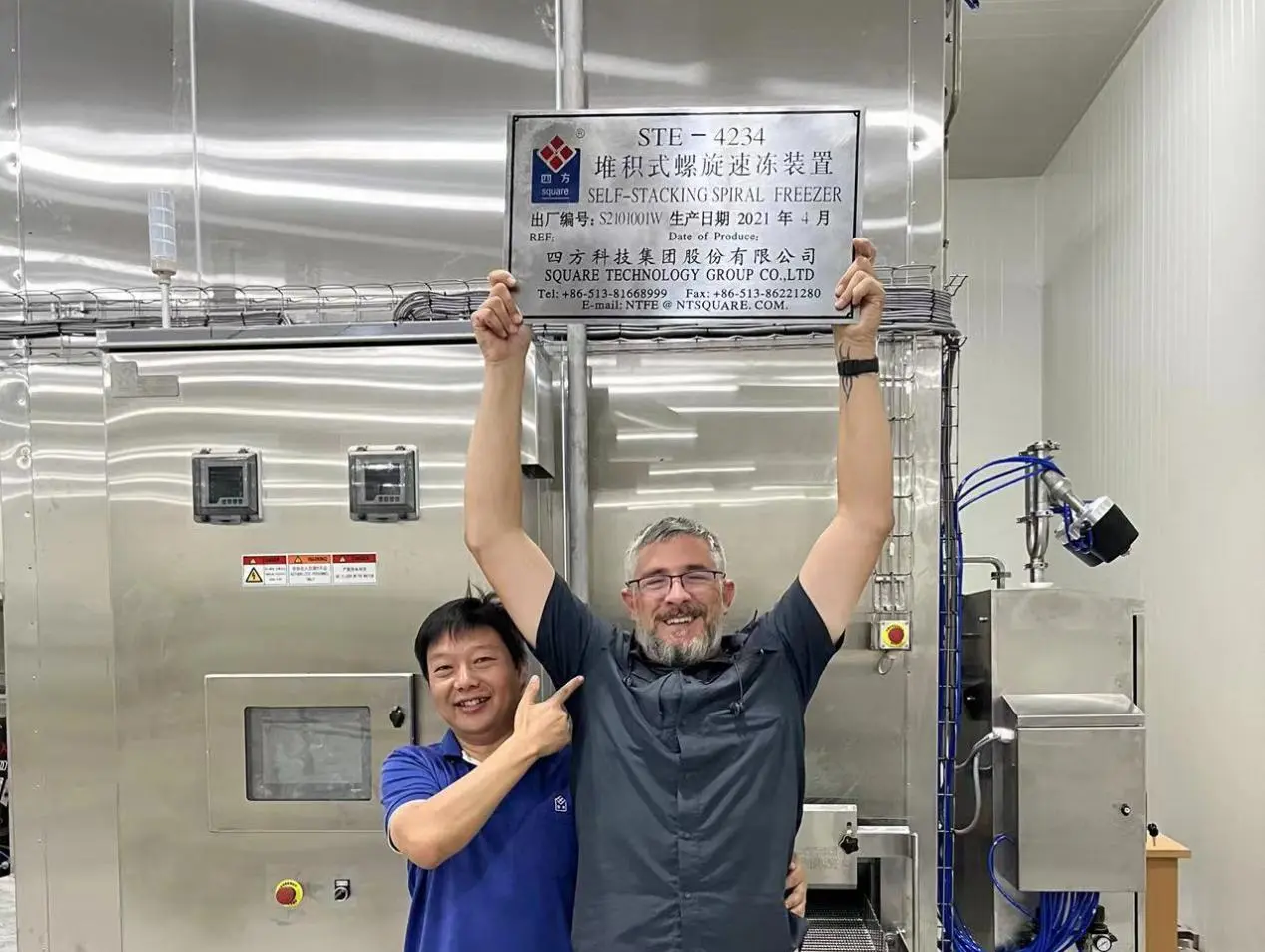Two Men Holding Up A Sign In Front Of A Machine